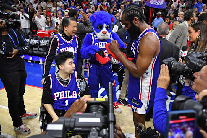 Philadelphia 76ers guard James Harden signs his shoes for a fan after a game.